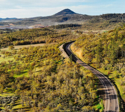 A wide aerial view of a valley with rolling hills, farmland, and forested areas during autumn